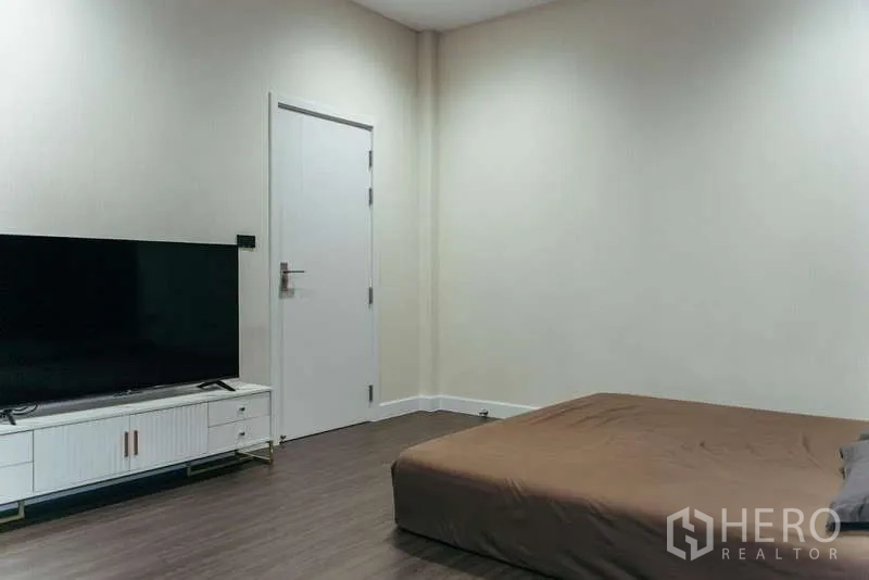 Detached House for sale in Sai Mai, Bangkok - Minimal bedroom with low bed, TV console and large flat‑screen.