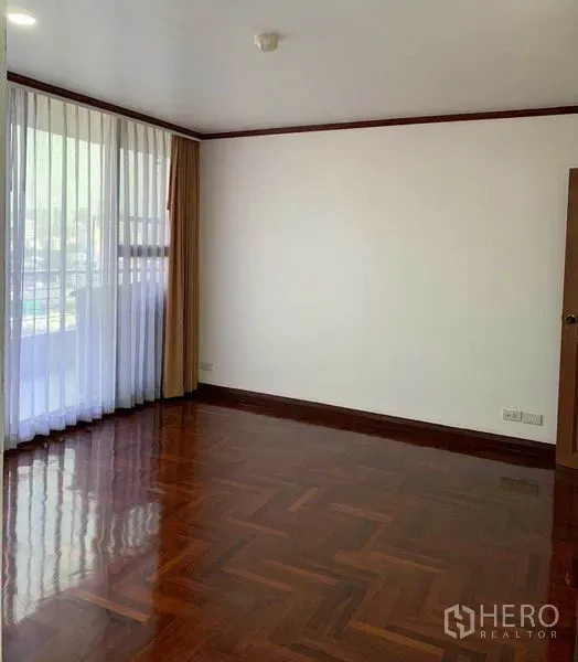 Condominium for rent or sale in Watthana, Bangkok - Sunlit bedroom featuring glossy parquet flooring and full-height curtains.