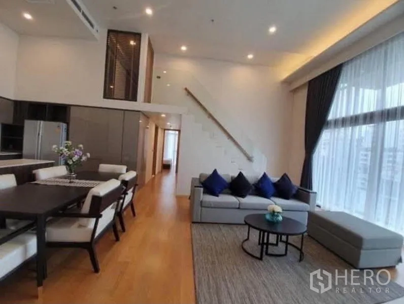 คอนโด ให้เช่าในWatthana, Bangkok - โถงนั่งเล่นกว้าง พื้นไม้ หมอนสีน้ำเงิน และบันไดขึ้นสู่โซนห้องนอน