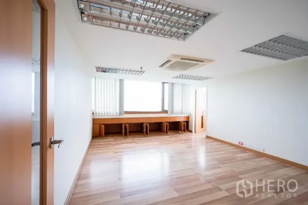 Office Space for rent in Pathum Wan, Bangkok - Spacious office room with light wood floors, long built-in workstations beneath the windows, and ceiling cassette AC.