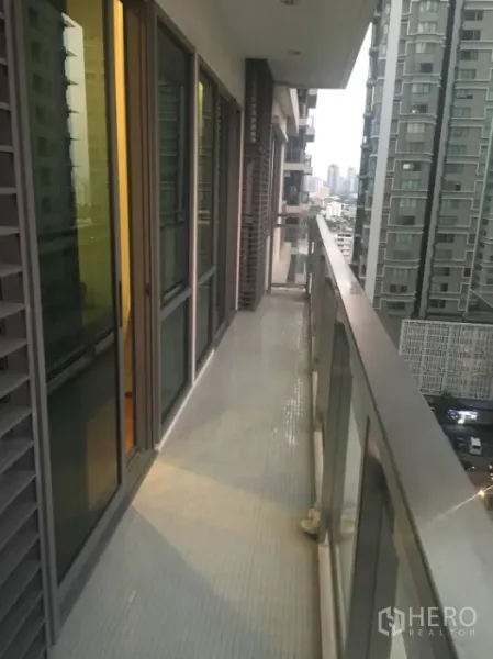 Condominium for rent in Khlong Toei, Bangkok - Long balcony with glass railing overlooking neighboring towers and the Bangkok skyline.