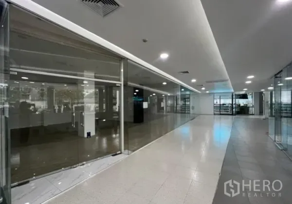 Retail Space for rent - Bright corridor of a retail mall with glass-walled shopfronts and recessed ceiling lights near BTS Phra Khanong.