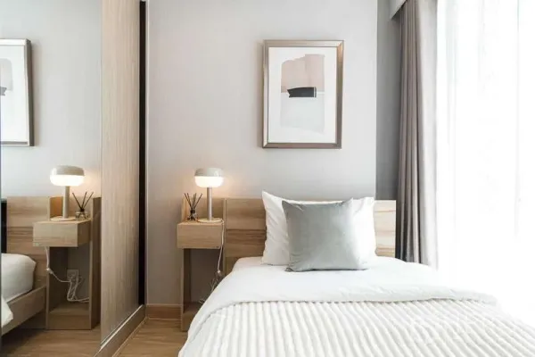 Condominium for rent - Bedroom corner with soft lighting, twin bedside tables and mirrored wardrobe.