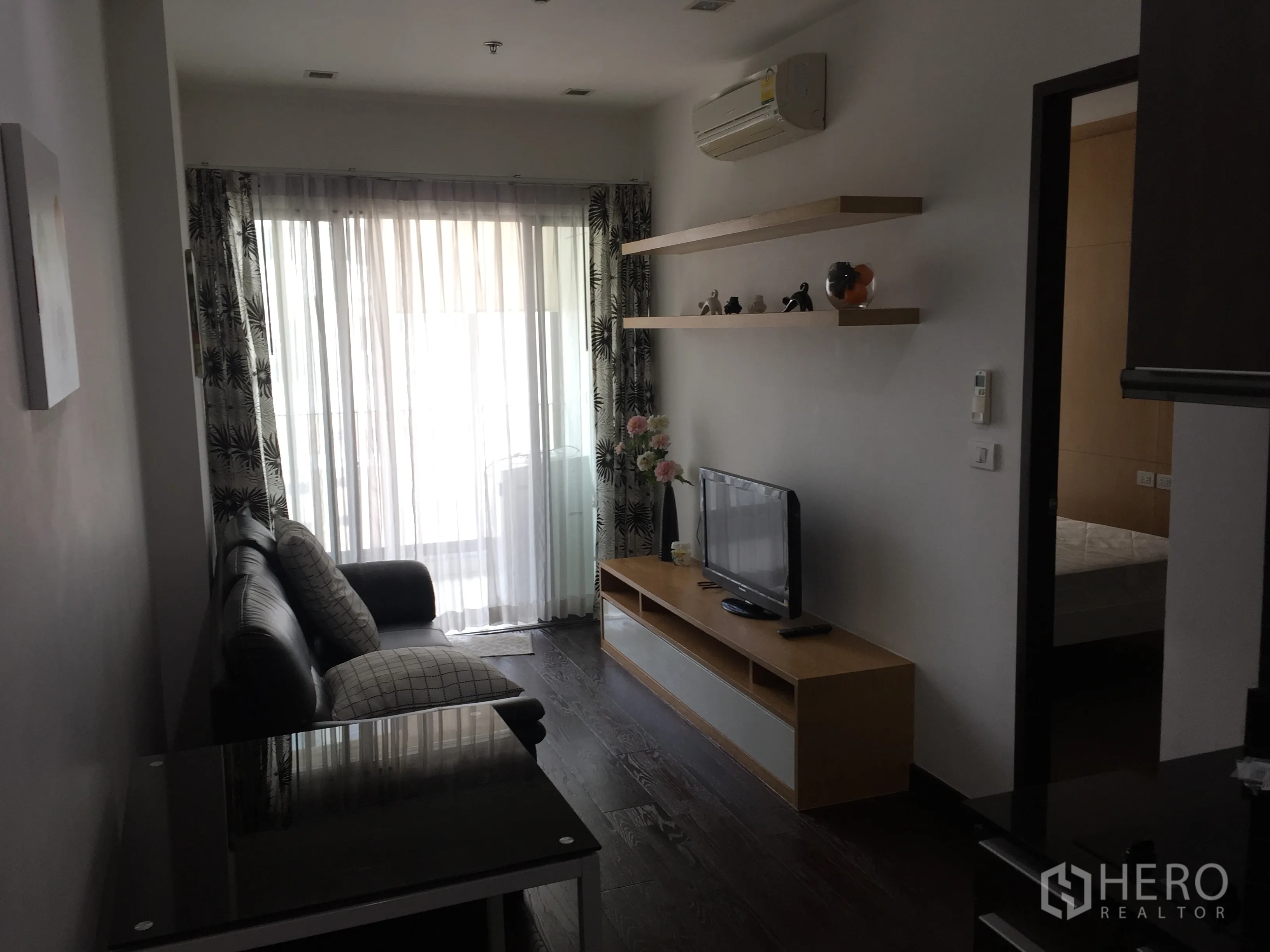公寓 出租在Ratchathewi, Bangkok - 明亮客厅，落地推拉玻璃、薄纱窗帘，配沙发与电视柜的现代公寓空间。