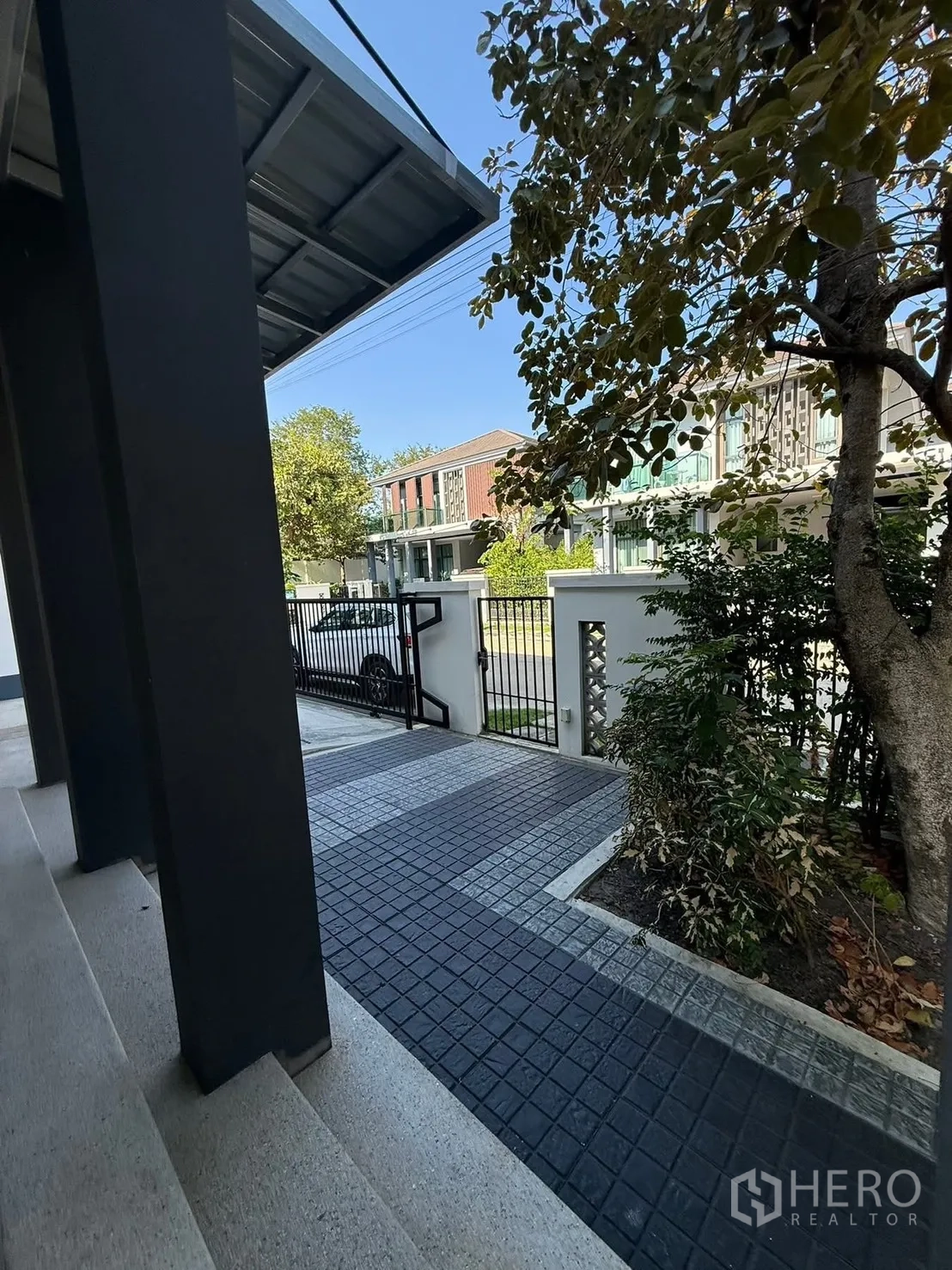 Detached House for rent in Prawet, Bangkok - Covered front porch and gated driveway with mature tree and paved path.