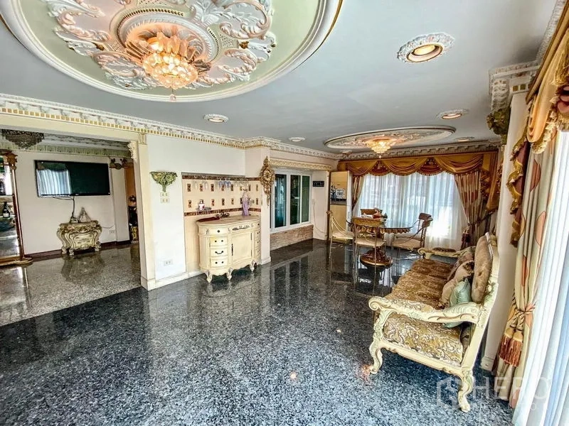 Detached House for rent or sale in Bang Khen, Bangkok - Open‑plan family room with ornate ceilings, stone flooring, gold drapes, and sliding glass doors to the terrace.