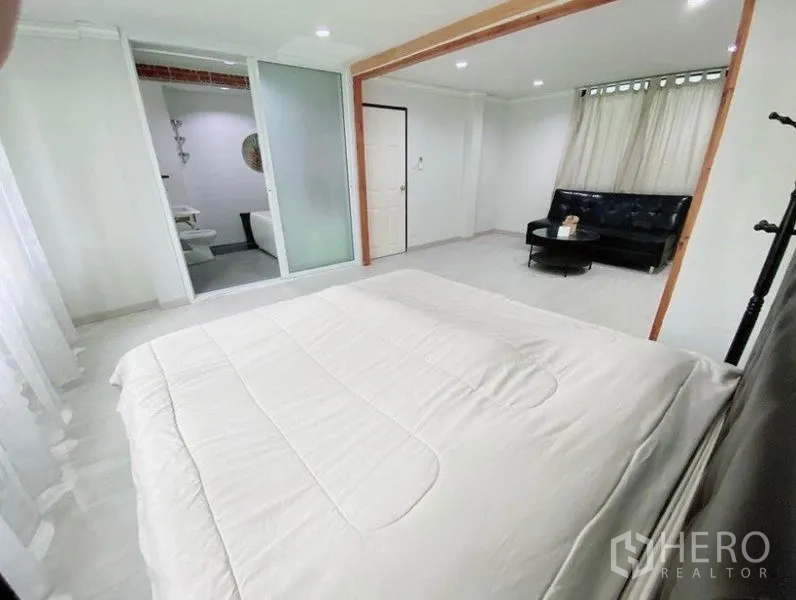 联排别墅 出租在Wang Thonglang, Bangkok - 宽敞卧室，落地窗、沙发角与套内卫生间入口。