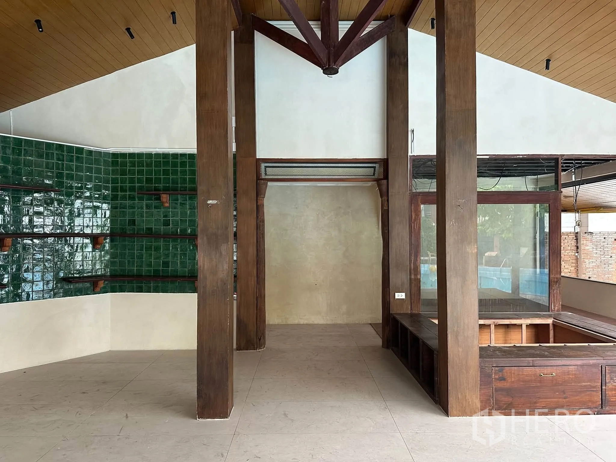 พื้นที่ขายของ for rent in Khlong Toei, Bangkok - พื้นที่โอเพ่นแพลน เสาไม้ เพดานทรงจั่ว ผนังกระเบื้องสีเขียว และเคาน์เตอร์จัดแสดง