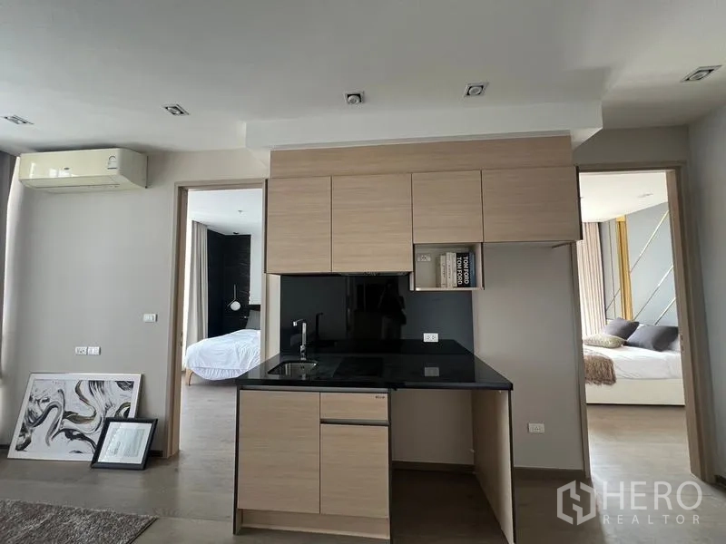 Condominium for sale - Compact kitchenette with black countertop and cabinetry between two bedrooms.