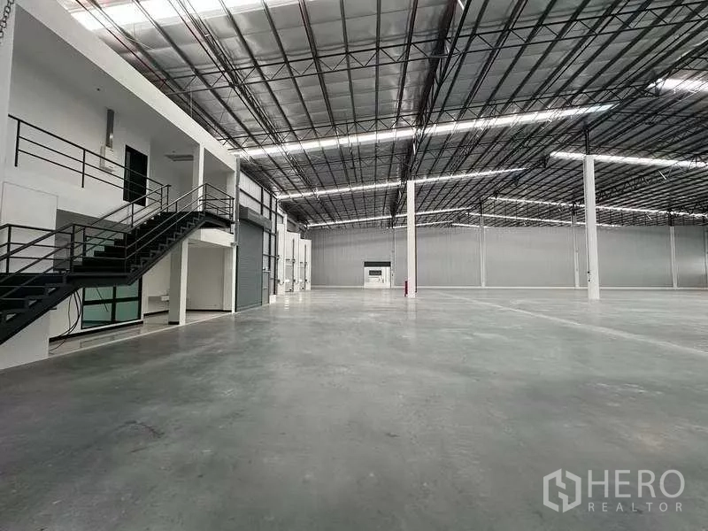 货栈 出租在Chon Buri - 仓库内部设夹层办公室、楼梯与卷帘门。
