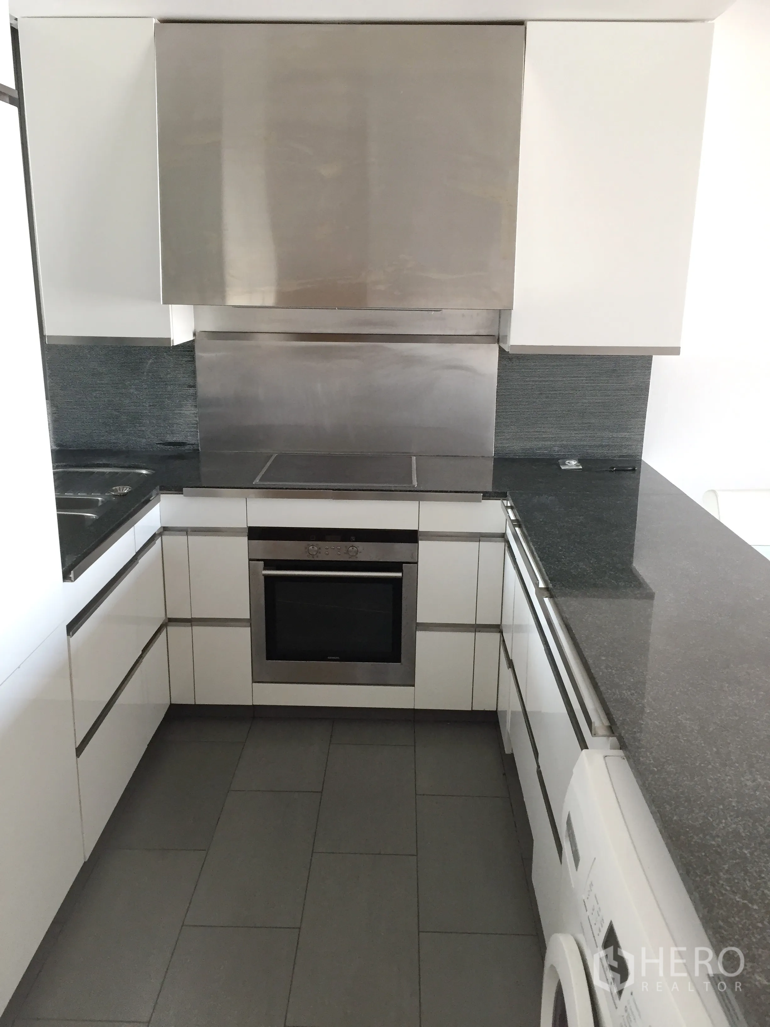 Condominium for sale in Sathon, Bangkok - Modern U‑shaped kitchen with stone countertops, built‑in oven and washer.