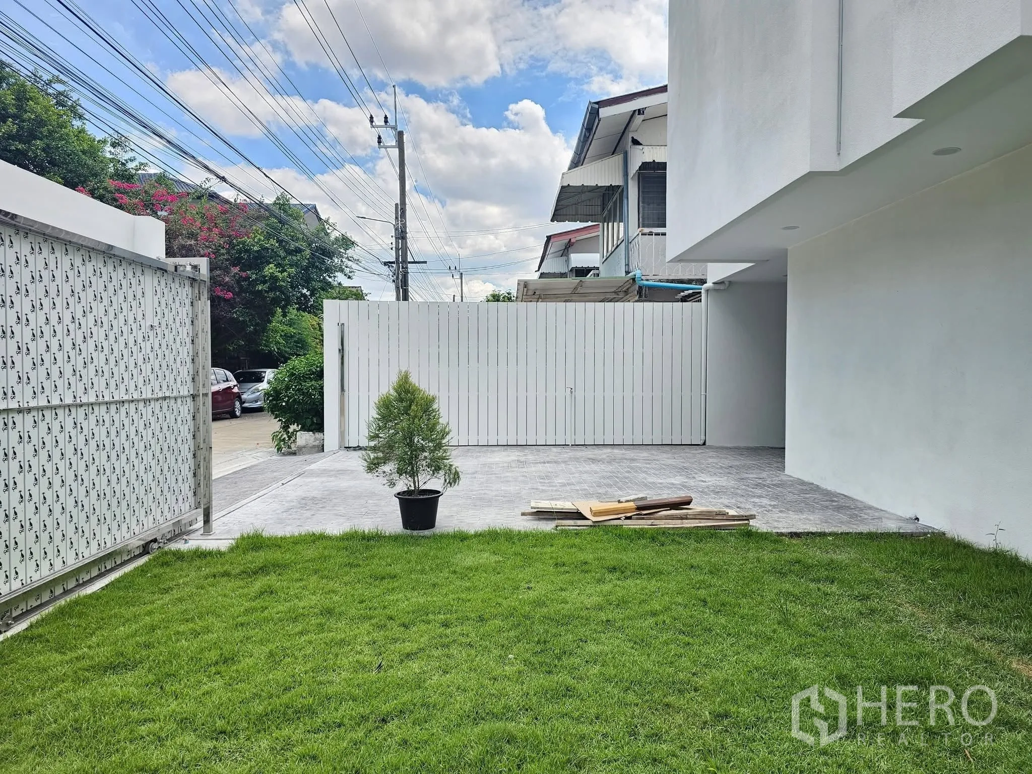 独栋房屋 for sale in Lat Phrao, Bangkok - 前院草坪与铺装车道，配有安全滑动大门。