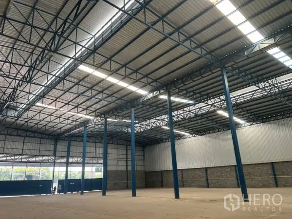 Warehouse for rent in Lat Krabang, Bangkok - Wide warehouse entrance with large blue gates and natural light panels.