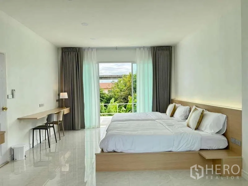 Detached House for rent in Lat Krabang, Bangkok - Bright bedroom with twin beds, floor‑to‑ceiling curtains and a balcony overlooking greenery.
