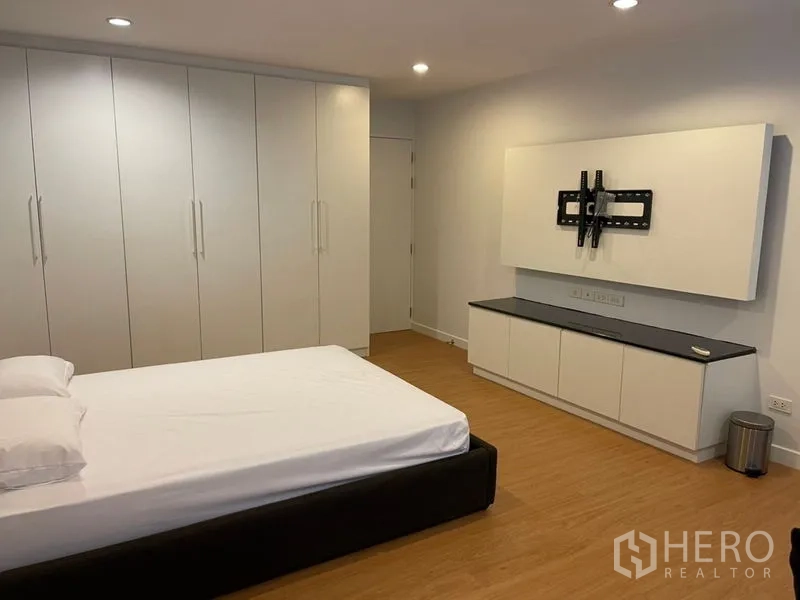 Townhouse for rent in Suan Luang, Bangkok - Bright bedroom with full-height wardrobes, wall TV mount and minimalist decor.