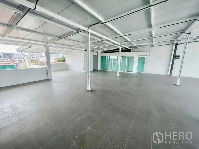 Home Office for rent or sale in Bang Kapi, Bangkok - Spacious open‑plan upper floor with tiled flooring, white steel beams, and sliding glass doors.