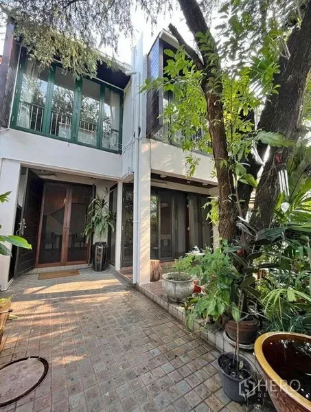 Townhouse for rent in Phaya Thai, Bangkok - Townhouse exterior with tiled courtyard, mature trees and potted plants.