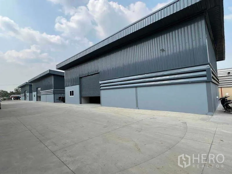 货栈 出租在Pathum Thani - 多座仓库外观，院区开阔，可停放摩托车。
