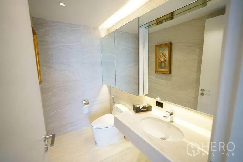 Condominium for rent or sale in Bang Na, Bangkok - Light bathroom with floating vanity, mirrored cabinets and contemporary toilet.