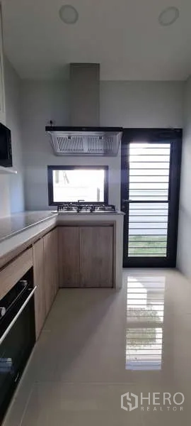 独立式住宅 出租在Lat Krabang, Bangkok - 厨房视角，带窗户与后门，地面光洁便于清洁通风。