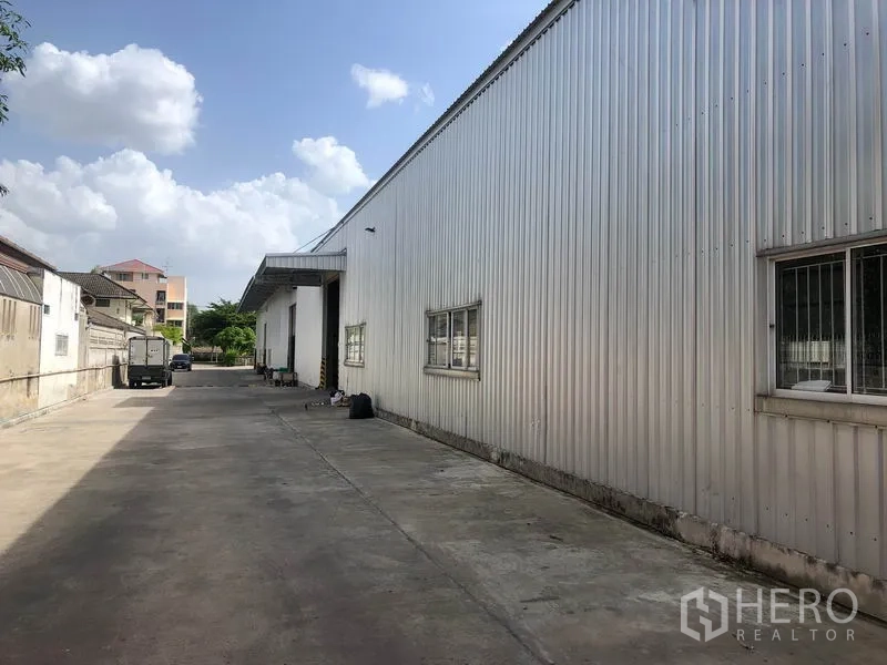 货栈 出租在Don Mueang, Bangkok - 仓库侧立面，长车道便于货车通行，旁有围墙。