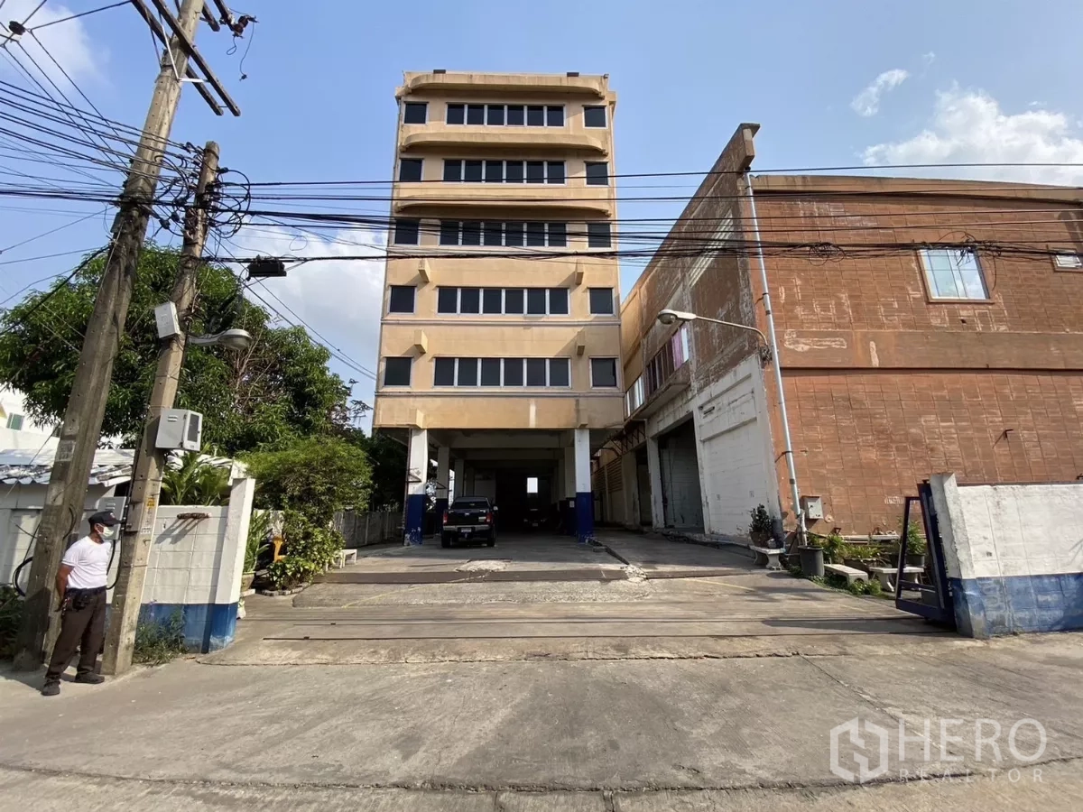 Factory for sale in Bang Phli, Samut Prakan - Street view of six-storey office building with covered drive-through beside factory.