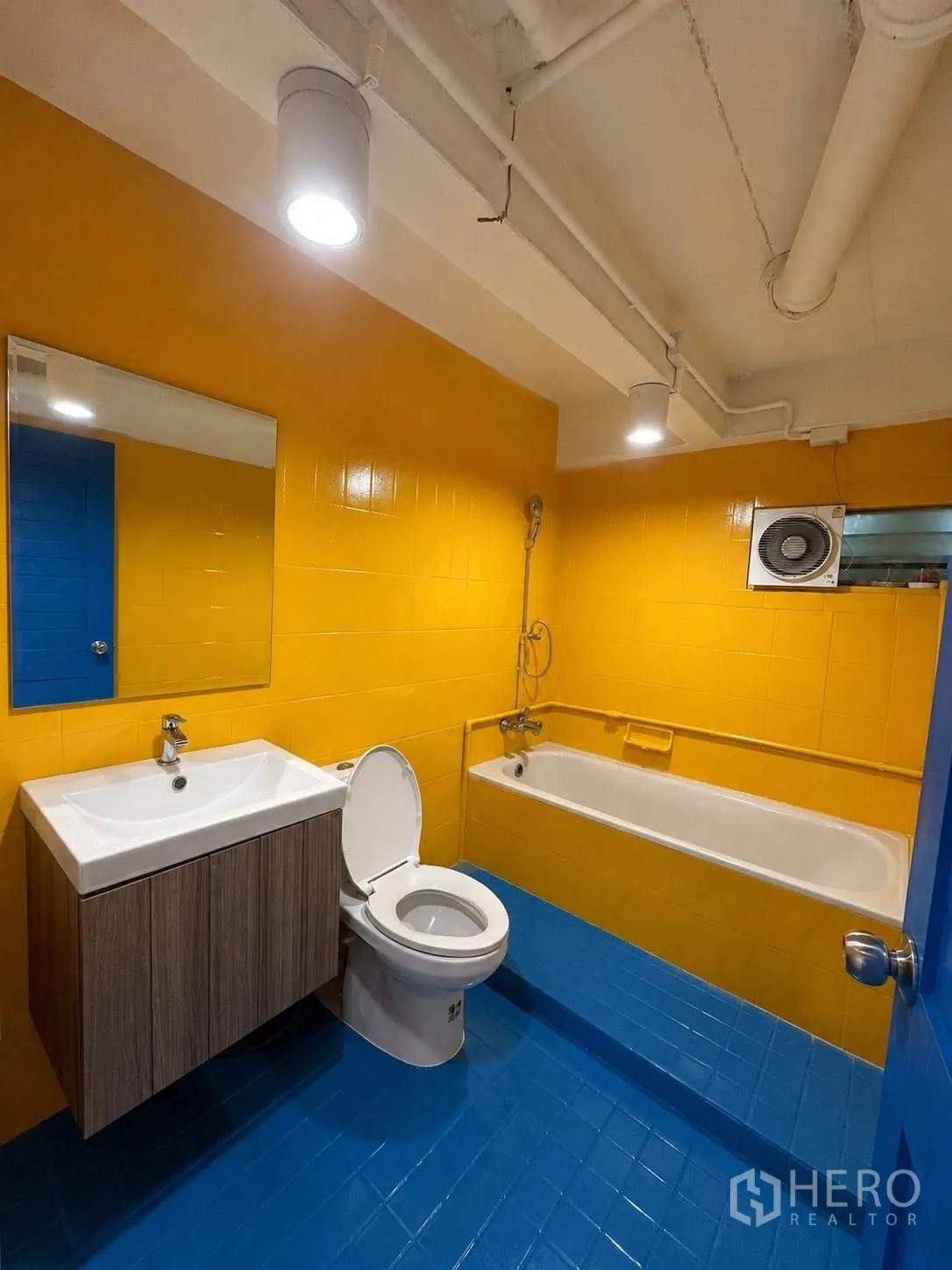 办公室 for rent in Phaya Thai, Bangkok - 色彩鲜明的卫生间，黄色墙面、蓝色地面和浴缸。