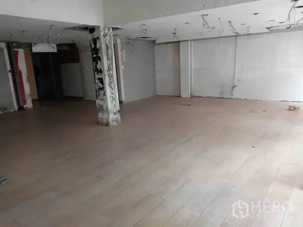 Retail Space for rent in Watthana, Bangkok - Open-plan retail interior with wood-look flooring, unfinished ceiling, and a central support column.