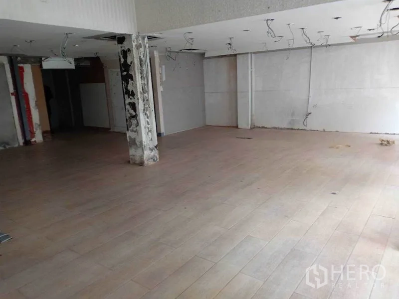 Retail Space for rent in Watthana, Bangkok - Open-plan retail interior with wood-look flooring, unfinished ceiling, and a central support column.