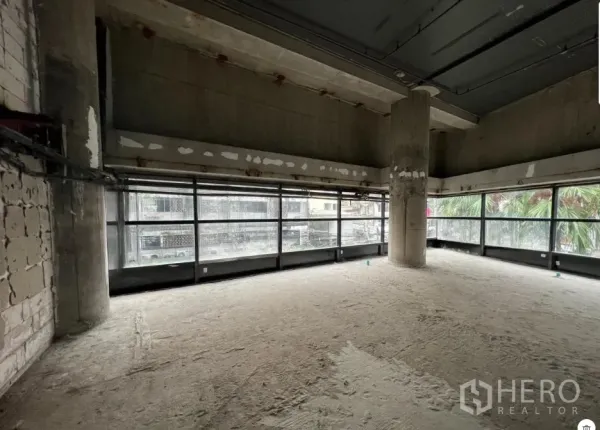 Retail Space for rent - Corner retail area with floor‑to‑ceiling glazing and a structural column in raw condition.