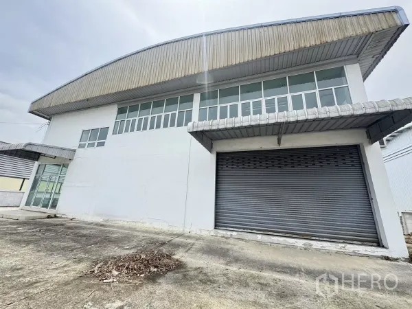 Warehouse for sale in Mueang Samut Prakan, Samut Prakan - Front view of a standalone warehouse with large roller shutter door and clerestory windows in Bang Pu.