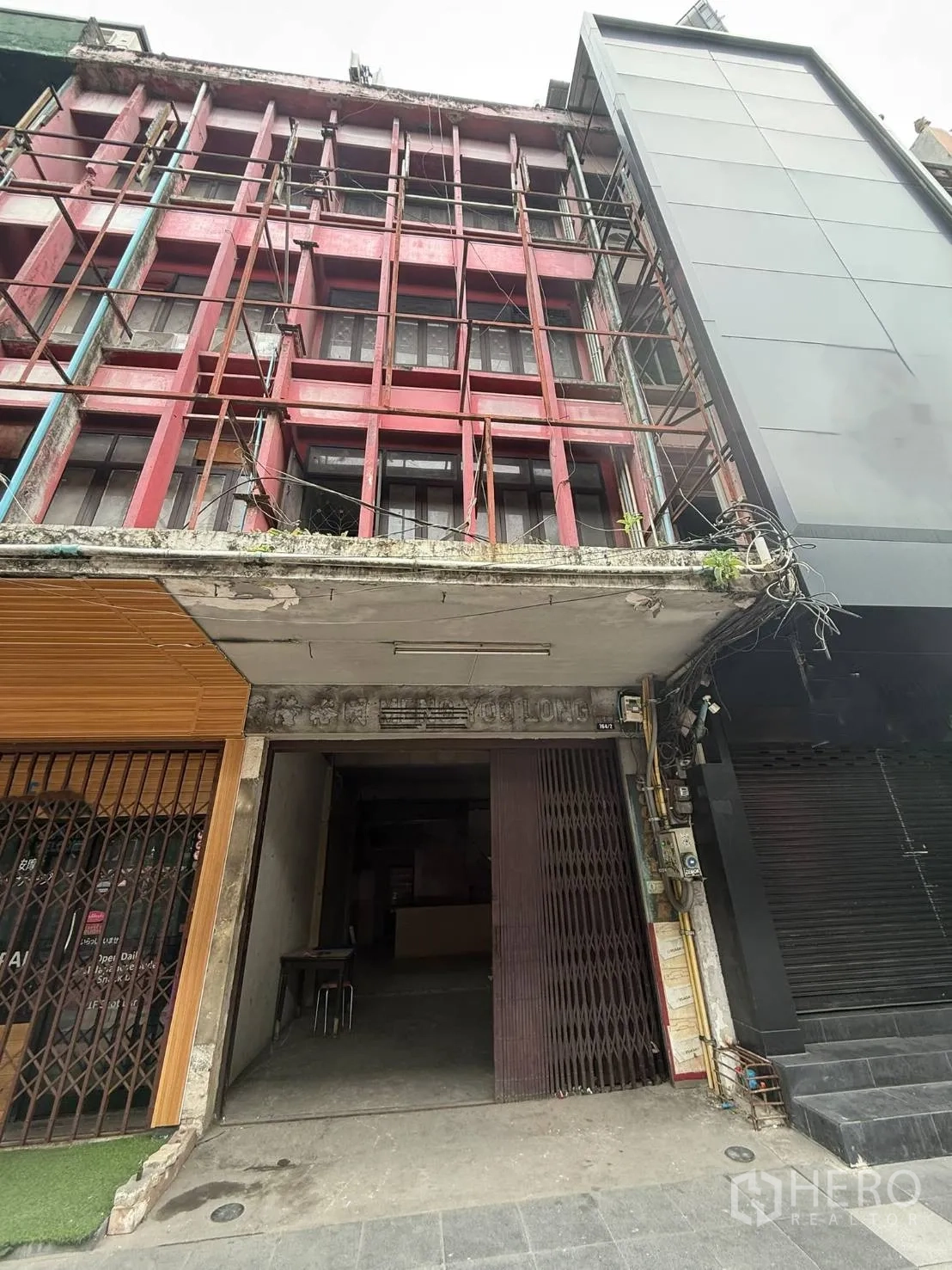 Shophouse for rent in Khlong Toei, Bangkok - Multi-storey shophouse exterior with a red facade and an open ground-floor entrance.