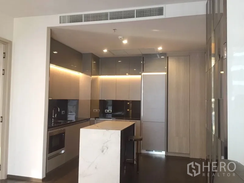 Condominium for rent in Watthana, Bangkok - Open-plan kitchen view with a marble island, built-in oven and glossy cabinets.