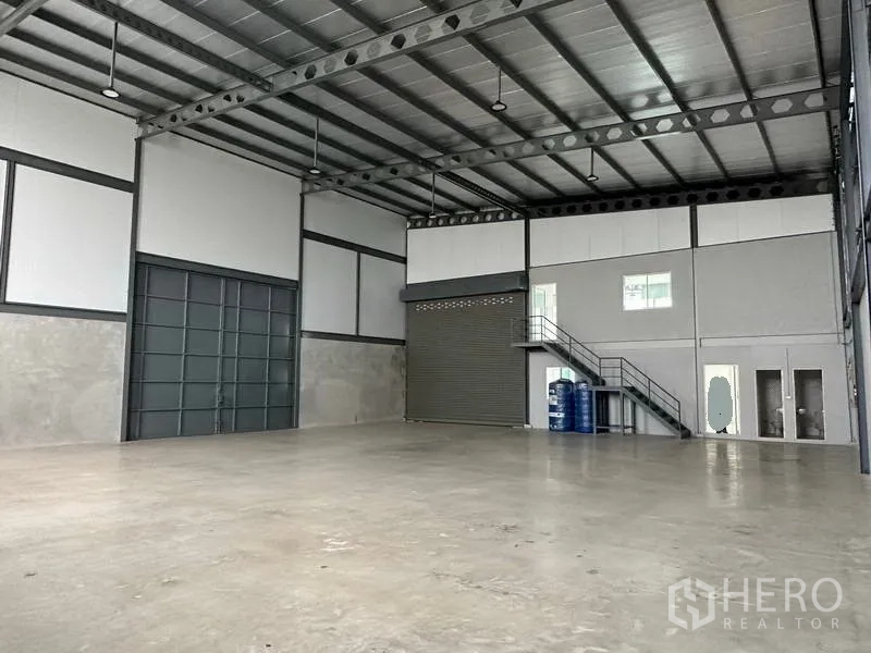 货栈 出租在Samut Prakan - 另一角度：大型推拉门、卷帘门及带楼梯的夹层办公室