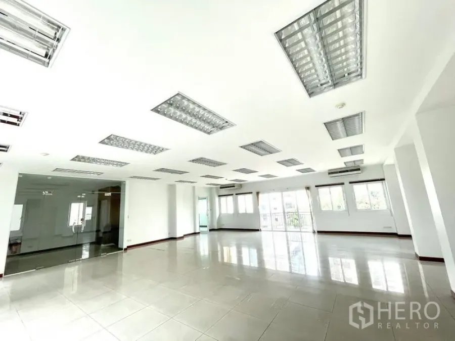 Office Space for rent in Bang Rak, Bangkok - Open workspace featuring a glass‑partitioned meeting room, multiple windows and fluorescent ceiling lights.