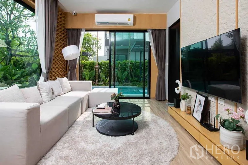 独立式住宅 出租或出售在Lat Krabang, Bangkok - 明亮客厅，超大电视与圆形茶几，面向泳池景。