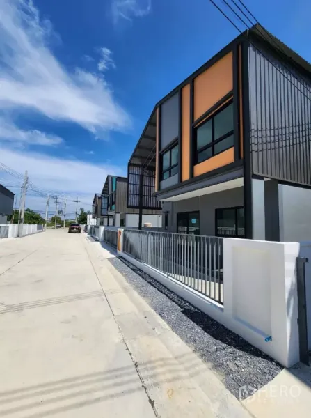 Factory for rent or sale in Bang Yai, Nonthaburi - Row of modern mini factory units with gated frontage along a wide concrete road in Bang Yai.