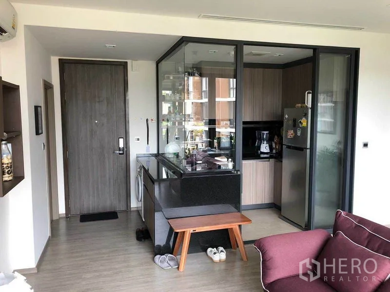 公寓 出租在Watthana, Bangkok - 入口区与玻璃隔断厨房，黑色花岗岩台面与木质柜体。