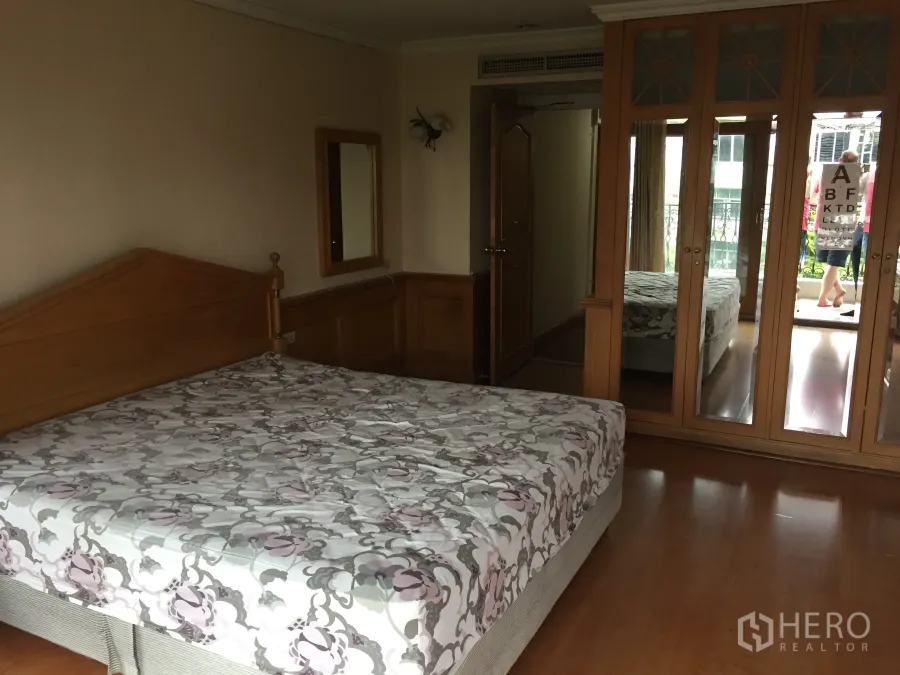 Condominium for rent in Khlong Toei, Bangkok - Master bedroom in a Phrom Phong condo with wooden floors, mirrored wardrobe and balcony access.