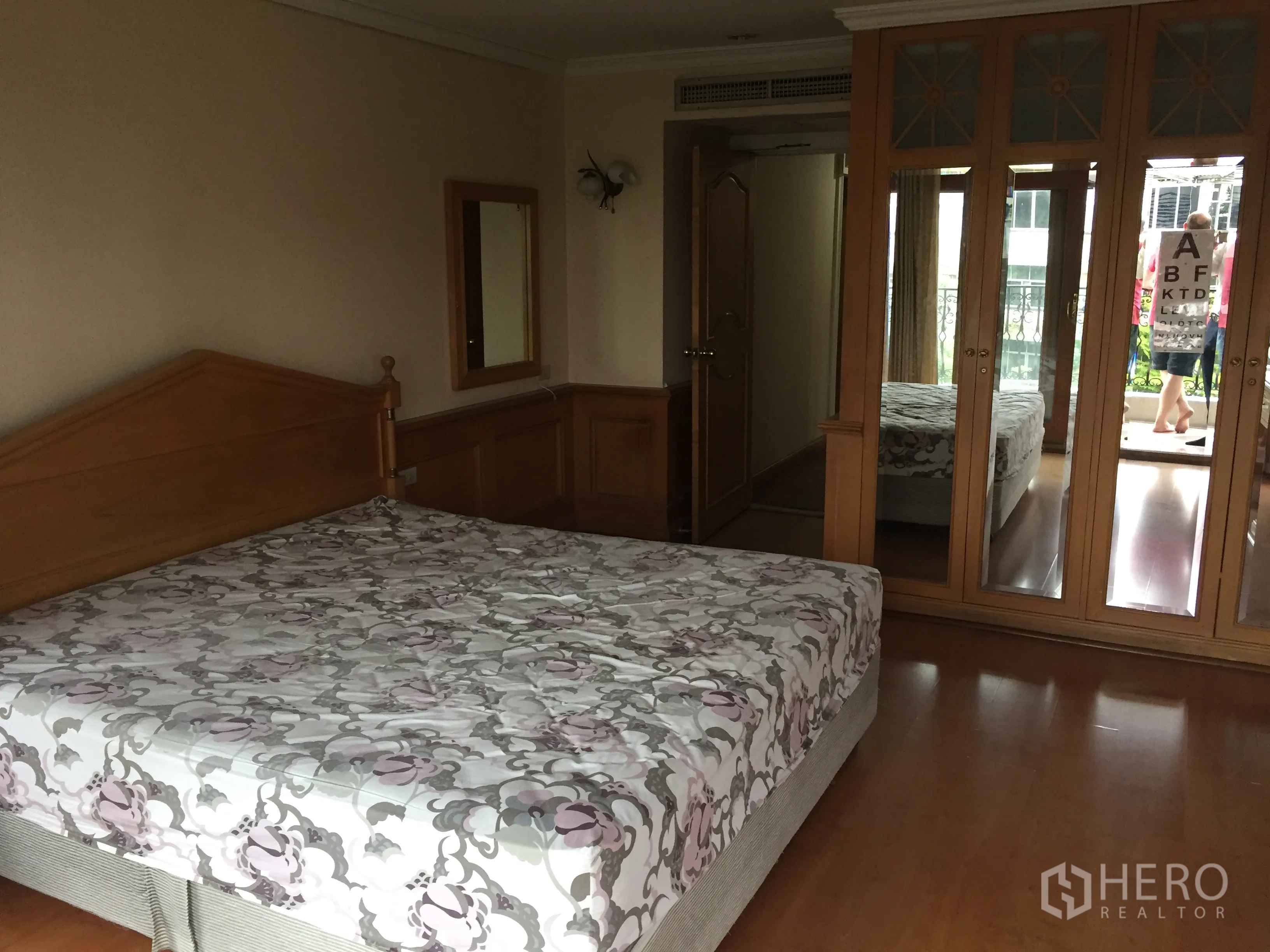 Condominium for rent in Khlong Toei, Bangkok - Master bedroom in a Phrom Phong condo with wooden floors, mirrored wardrobe and balcony access.
