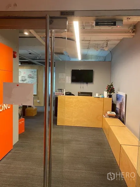 Office Space for rent in Khlong Toei, Bangkok - Glass entry door opening to a reception with bench seating and warm wood finishes.