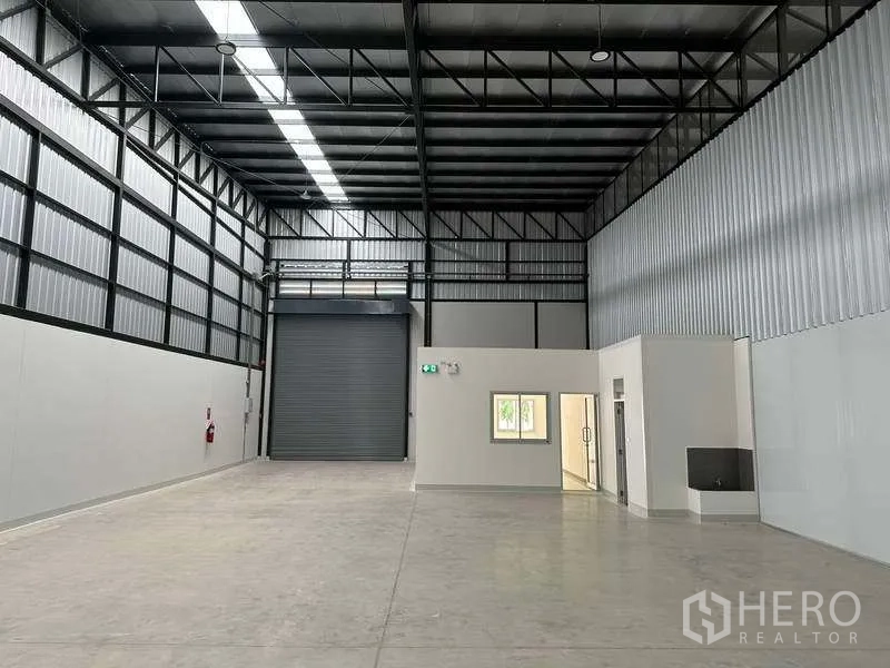 工厂 出租在Bang Phli, Samut Prakan - 厂房内部朝向卷帘门，高挑空间与内建办公区