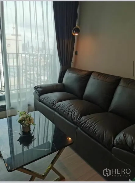 คอนโด ให้เช่าในHuai Khwang, Bangkok - โซฟาหนังข้างหน้าต่างเต็มสูงชมวิวสกายไลน์