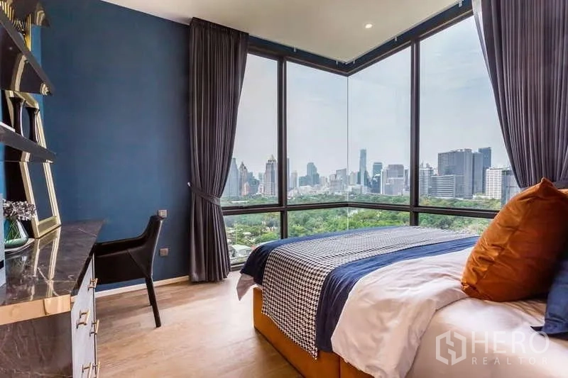 Condominium for rent in Pathum Wan, Bangkok - Bedroom corner windows framing Lumpini Park and the Bangkok skyline.