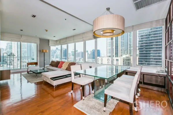Condominium for rent or sale in Khlong Toei, Bangkok - Dining area with glass table beside corner windows overlooking the city.