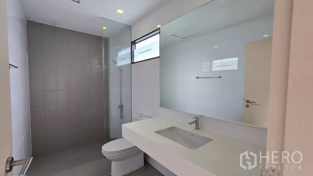 Townhouse for rent or sale in Saphan Sung, Bangkok - Upper-floor bathroom with wide vanity, toilet and walk-in shower.