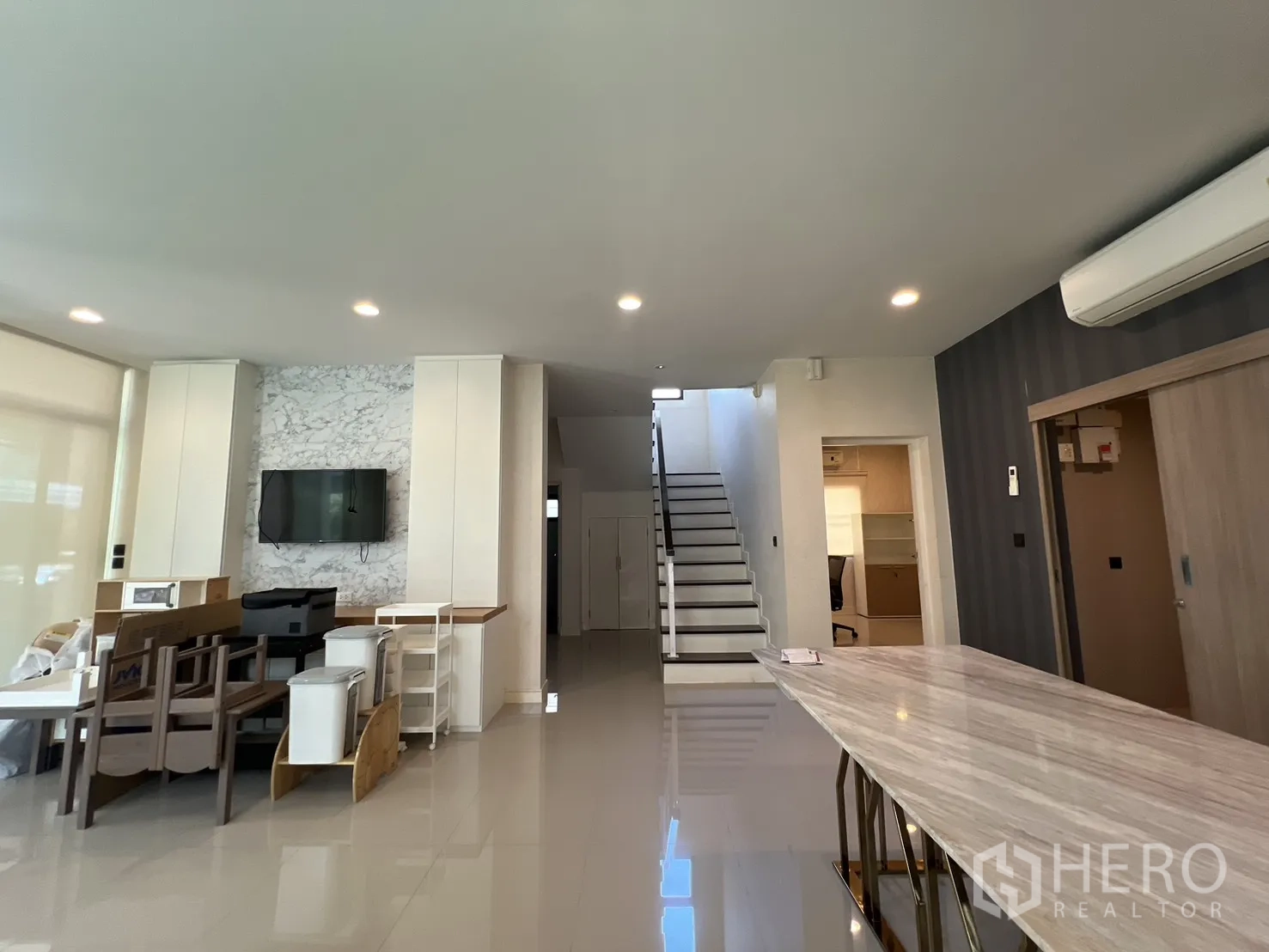 Detached House for sale in Bang Kapi, Bangkok - Living and dining space with marble feature wall, staircase, and long island table.