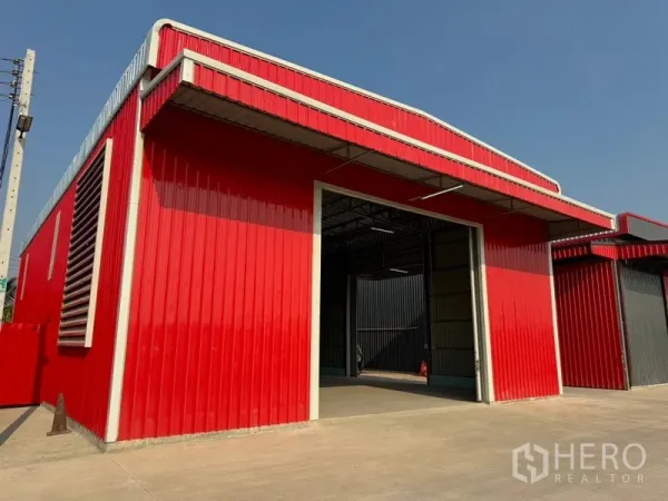 Warehouse for rent in Lam Luk Ka, Pathum Thani - Front view of a red warehouse unit with high opening and spacious concrete forecourt.