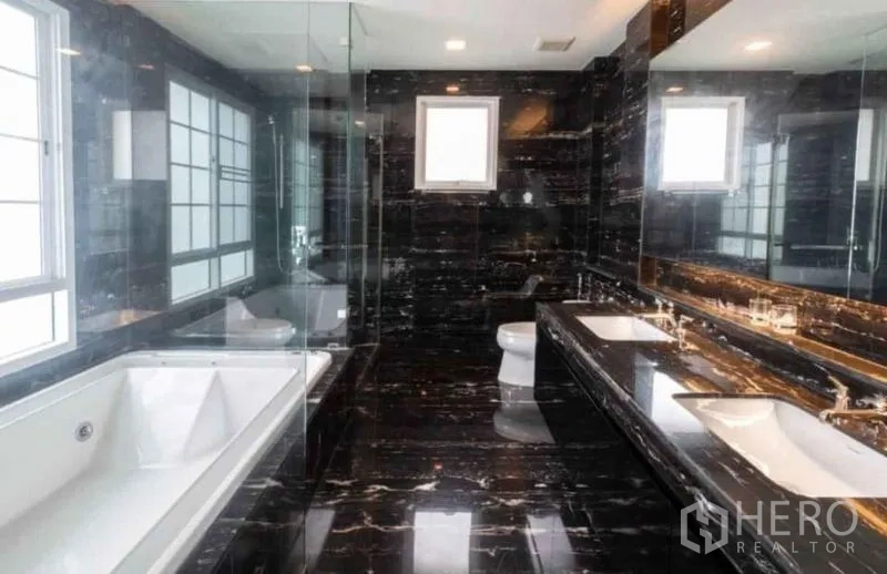 Detached House for rent or sale in Bang Phli, Samut Prakan - Luxurious bathroom clad in black marble with bathtub, double vanity and glass shower.