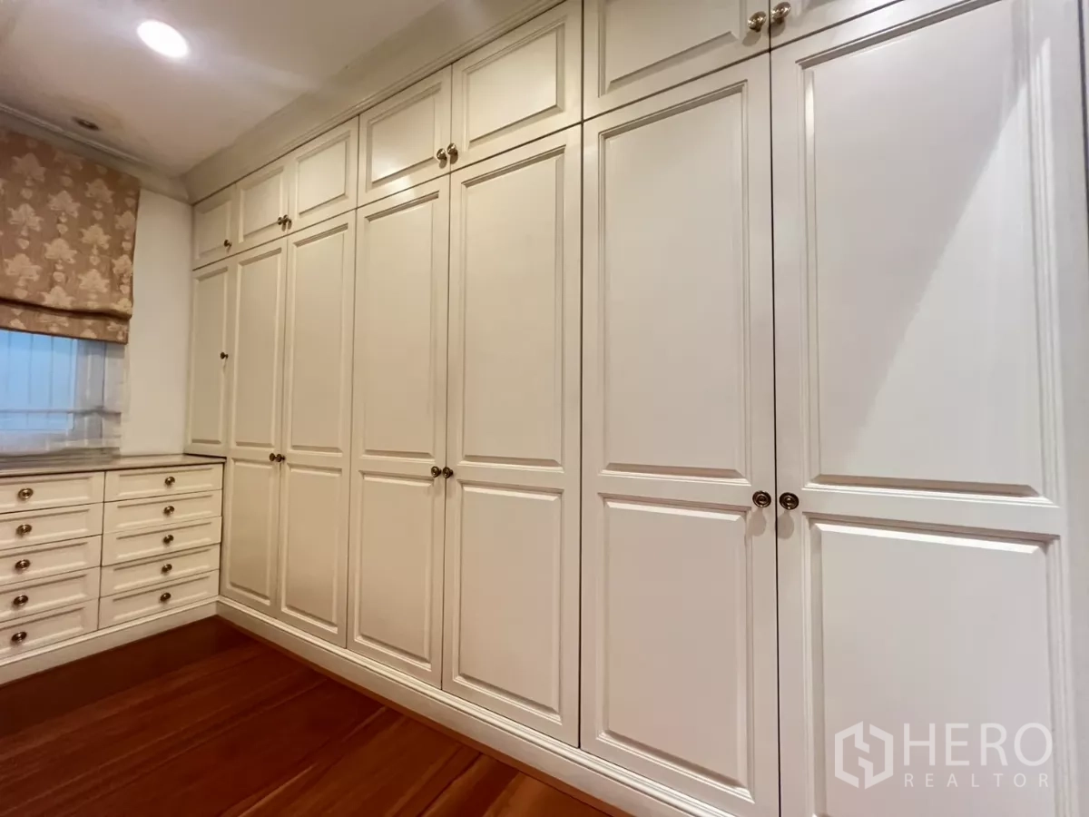 Townhouse for sale in Watthana, Bangkok - Walk-in closet with wall-to-wall white cabinetry and drawers.